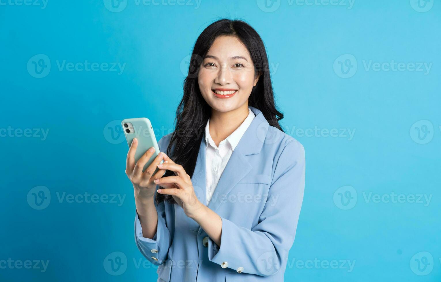 portrait of young asian businesswoman posing on blue background photo