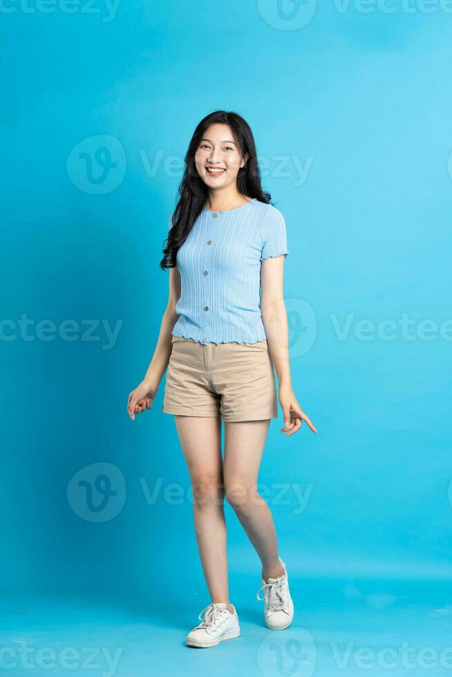 Portrait of smiling asian woman posing on blue background photo