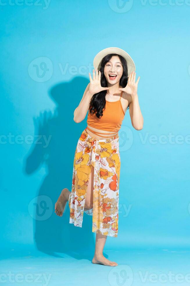 imagen de alegre sonriente asiático mujer en traje de baño, aislado en azul antecedentes foto