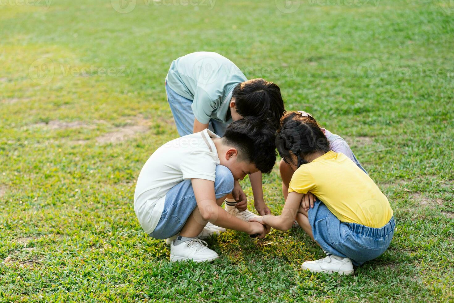 image of asian kids using magnifying glass in park photo