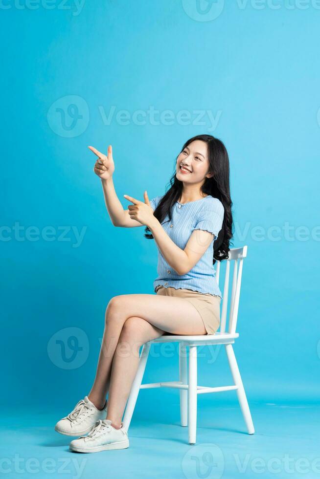 Portrait of smiling asian woman posing on blue background photo