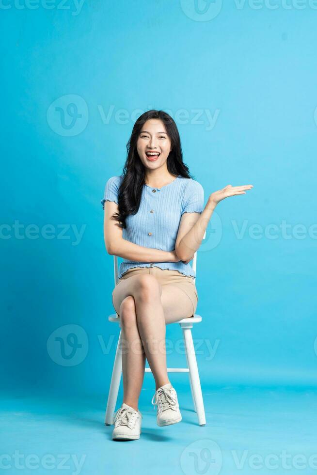 retrato de sonriente asiático mujer posando en azul antecedentes foto