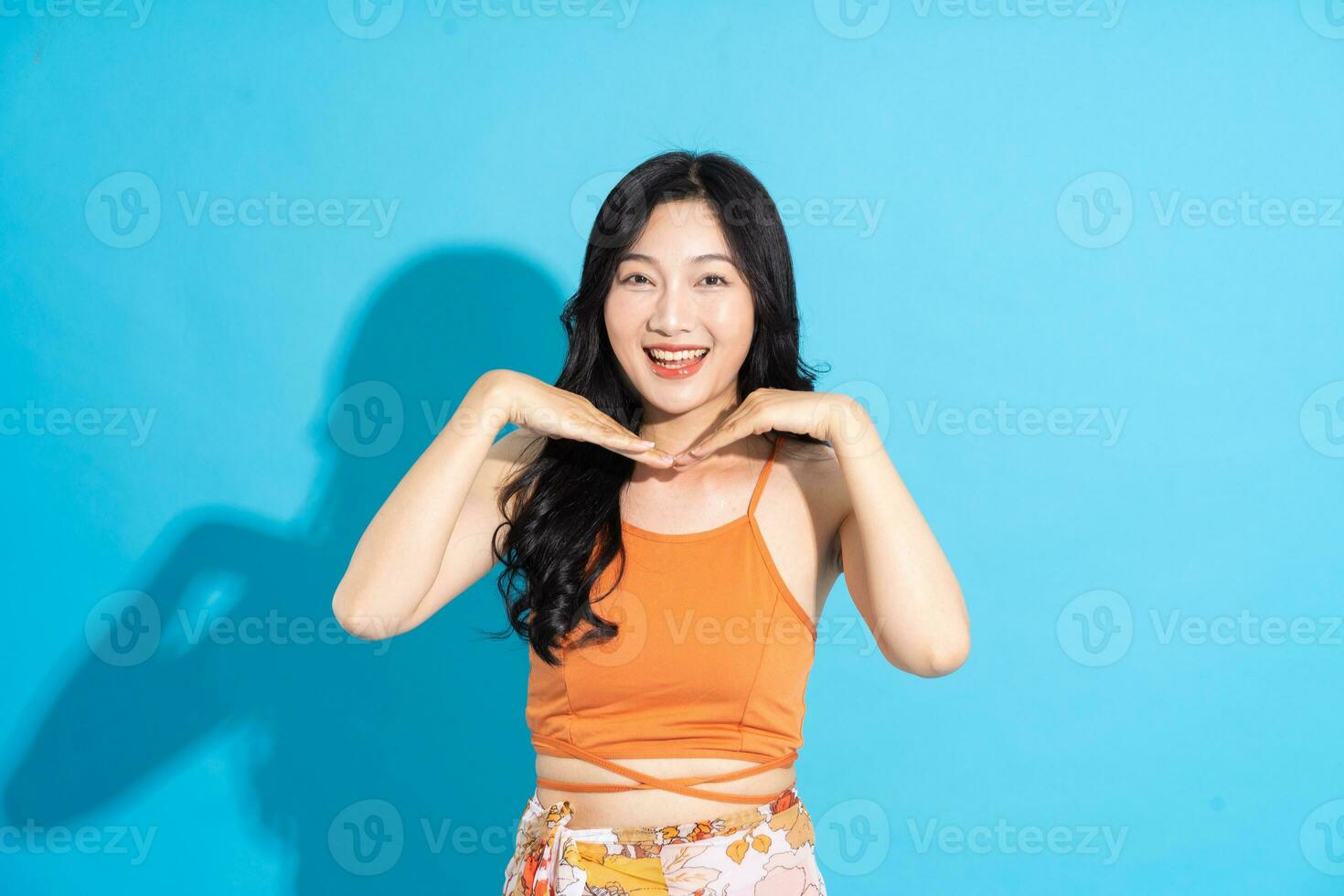 Portrait of a beautiful asian girl in a swimsuit smiling happily on a blue background photo