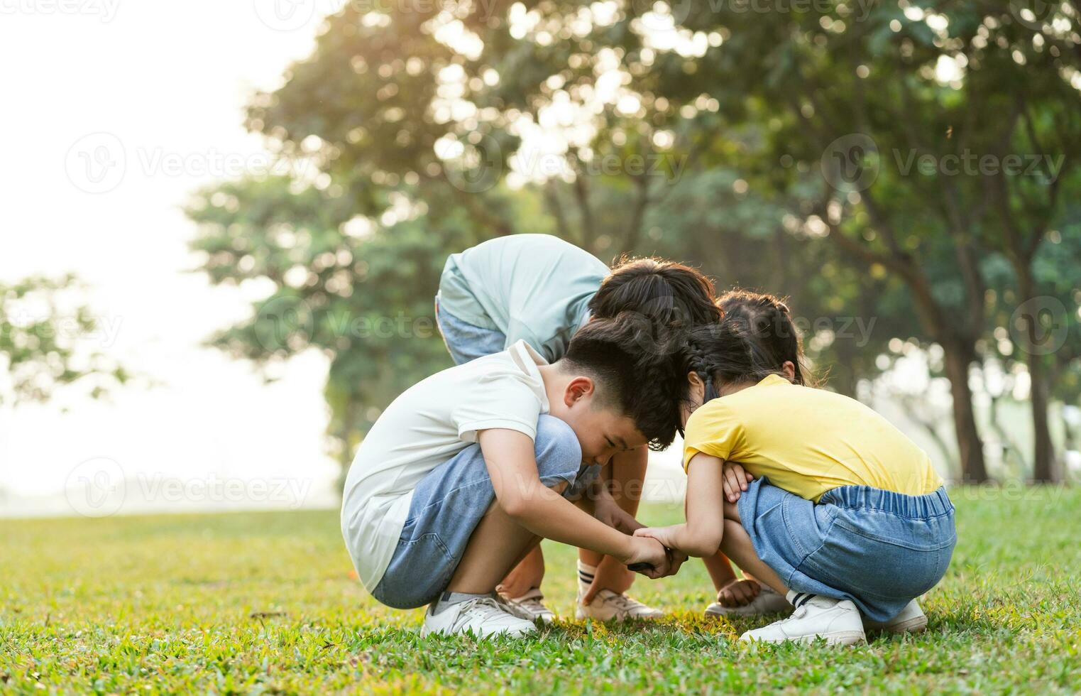 image of asian kids using magnifying glass in park photo