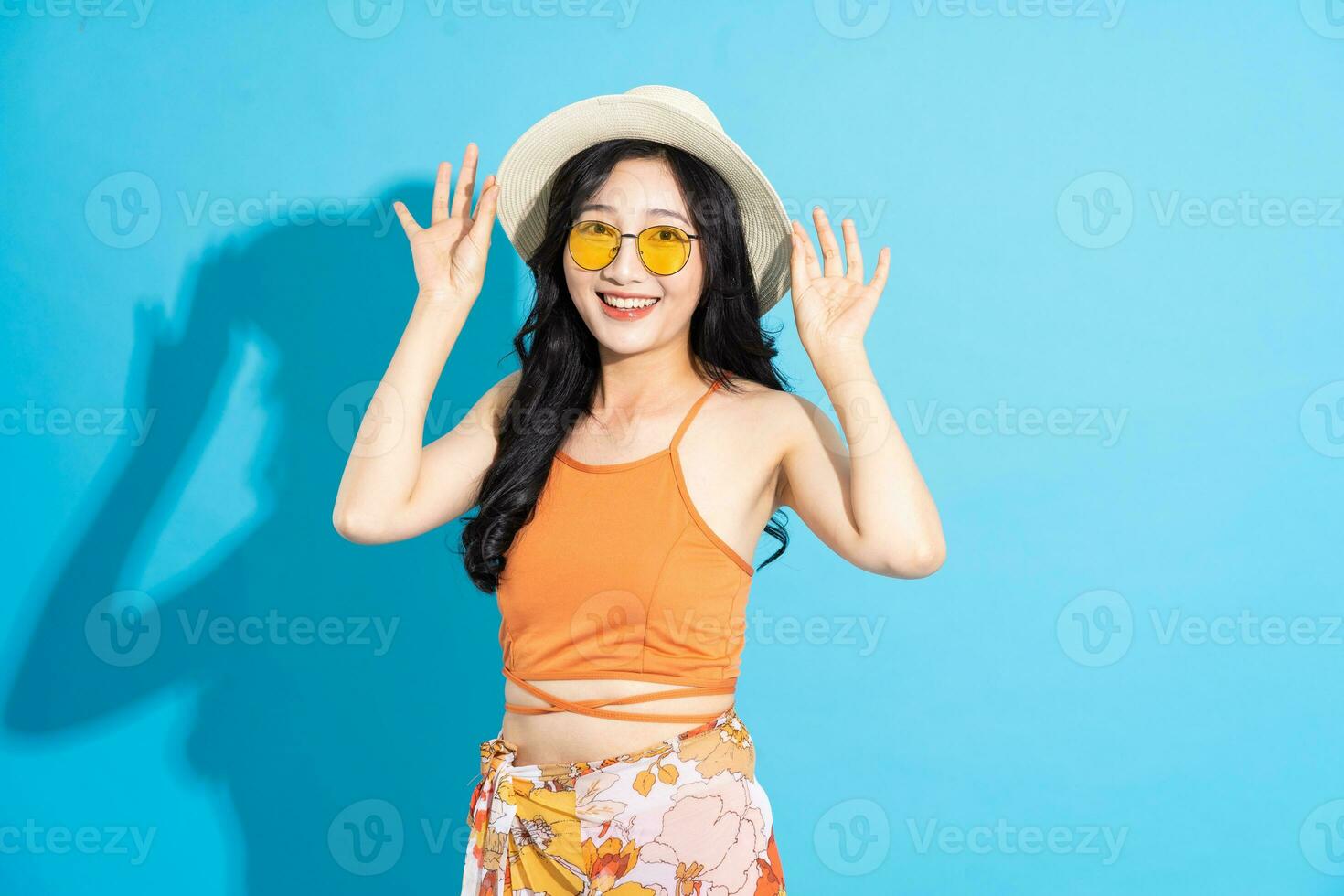 Portrait of a beautiful asian girl in a swimsuit smiling happily on a blue background photo