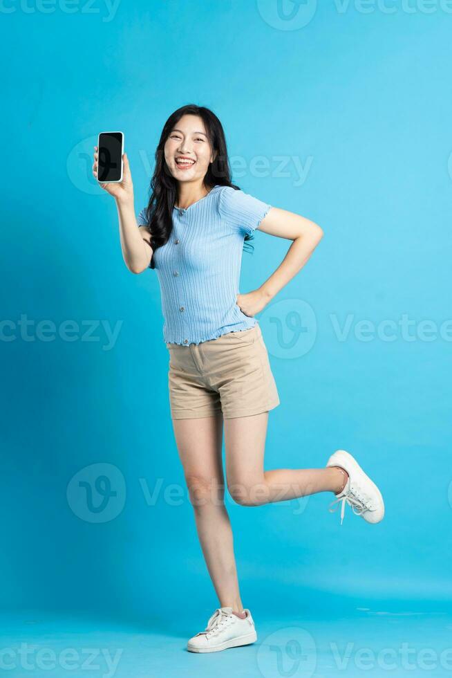 full body image of beautiful asian girl posing on blue background photo
