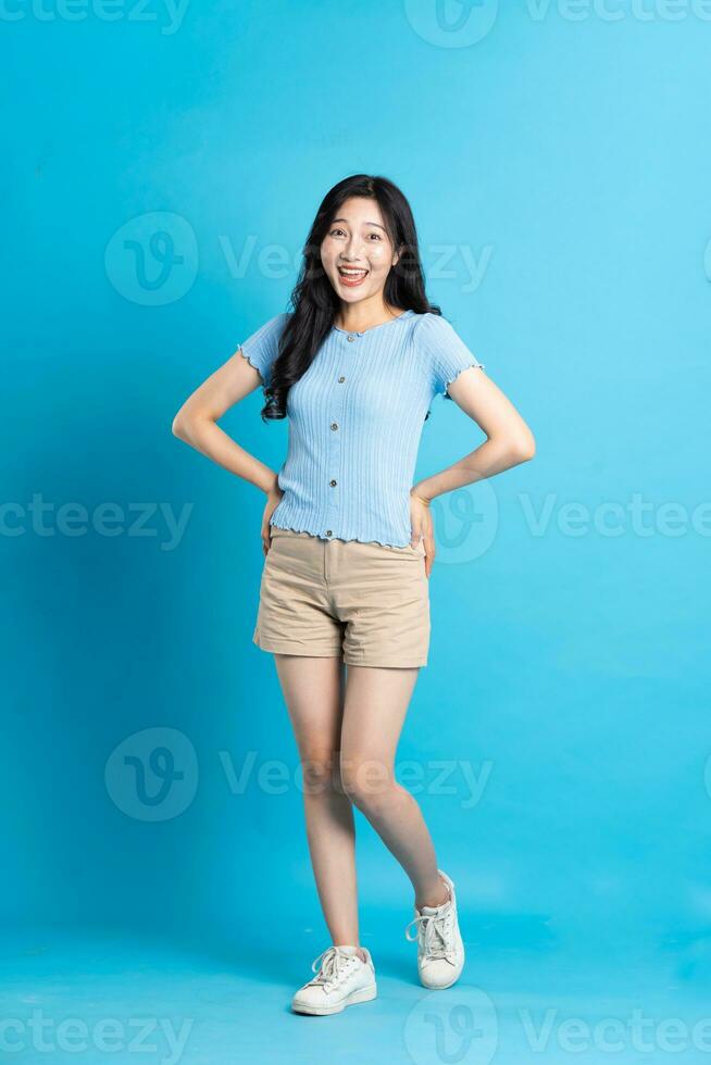 full body image of beautiful asian girl posing on blue background photo