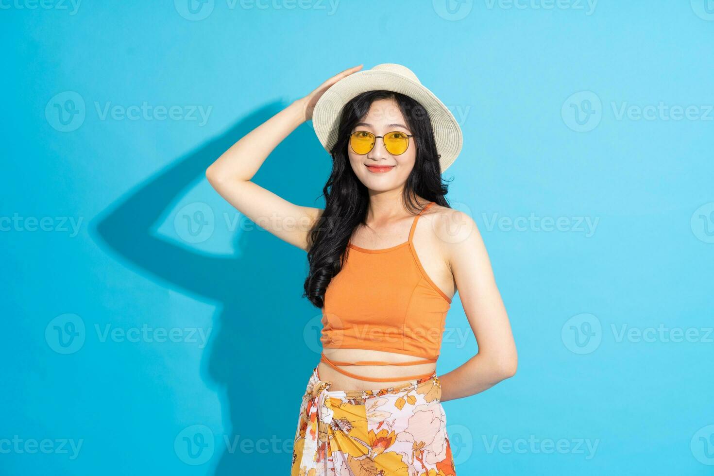 Portrait of a beautiful asian girl in a swimsuit smiling happily on a blue background photo