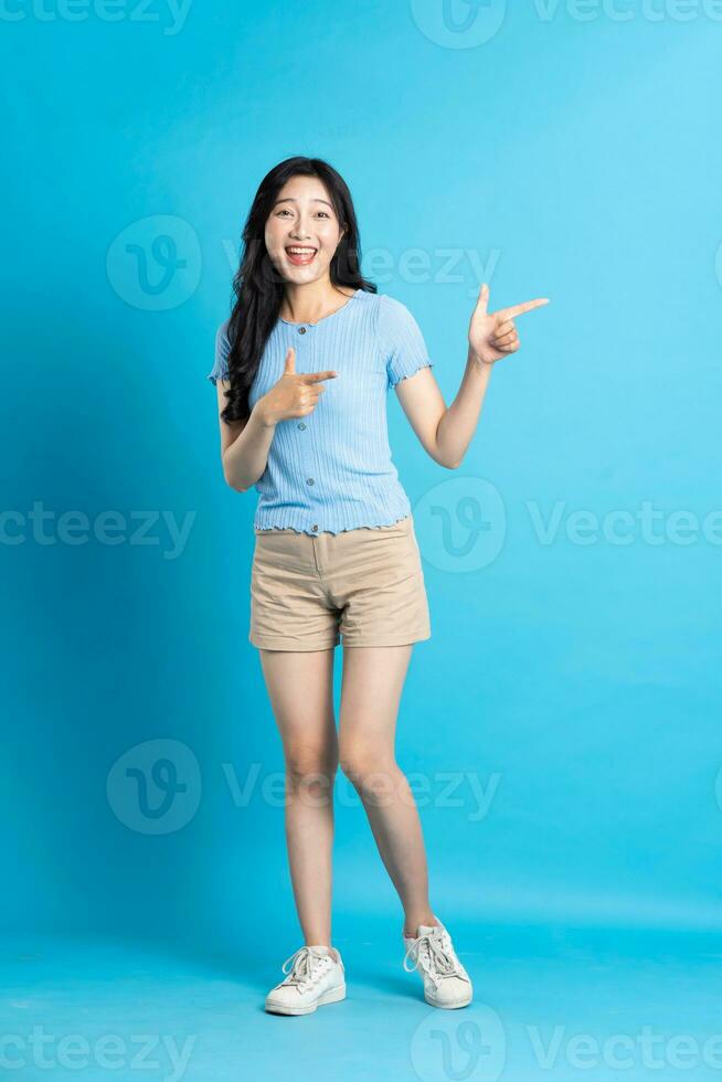 Portrait of smiling asian woman posing on blue background photo