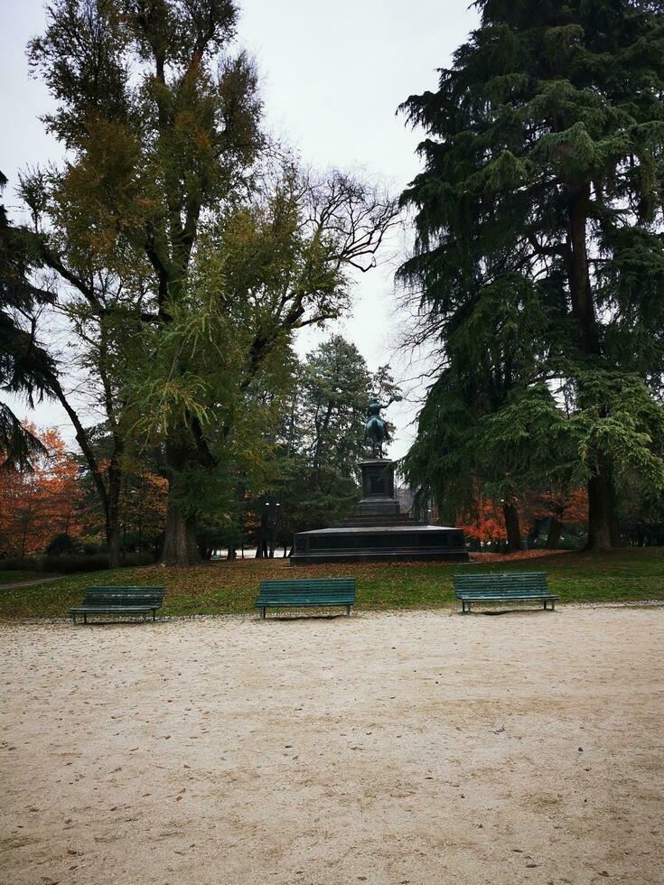 Park in autumn with a bench and a statue in the foreground. photo