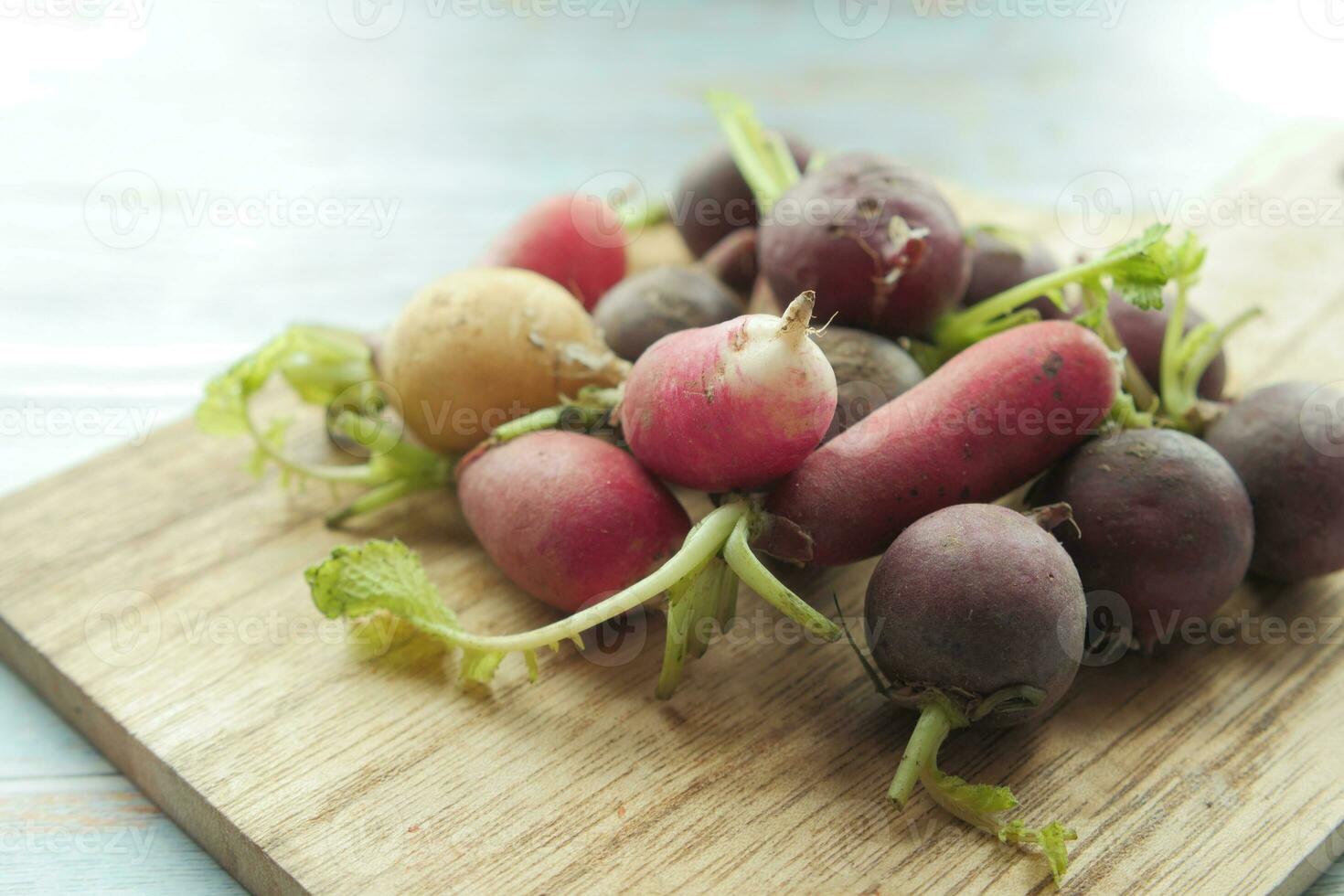 Fresh red radish bundle on chopping board on table photo