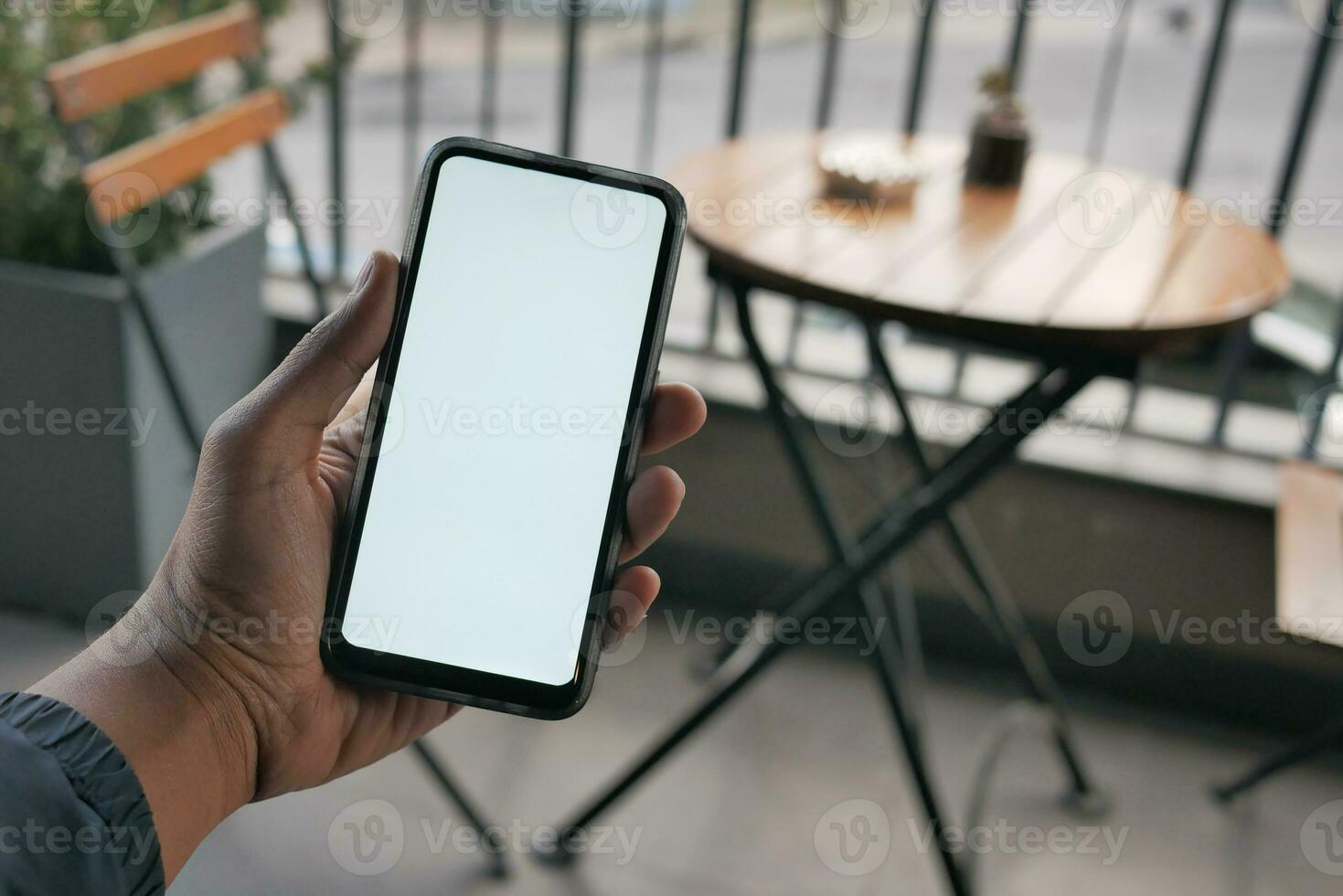 mano de hombre joven usando un teléfono inteligente con pantalla verde en el café foto