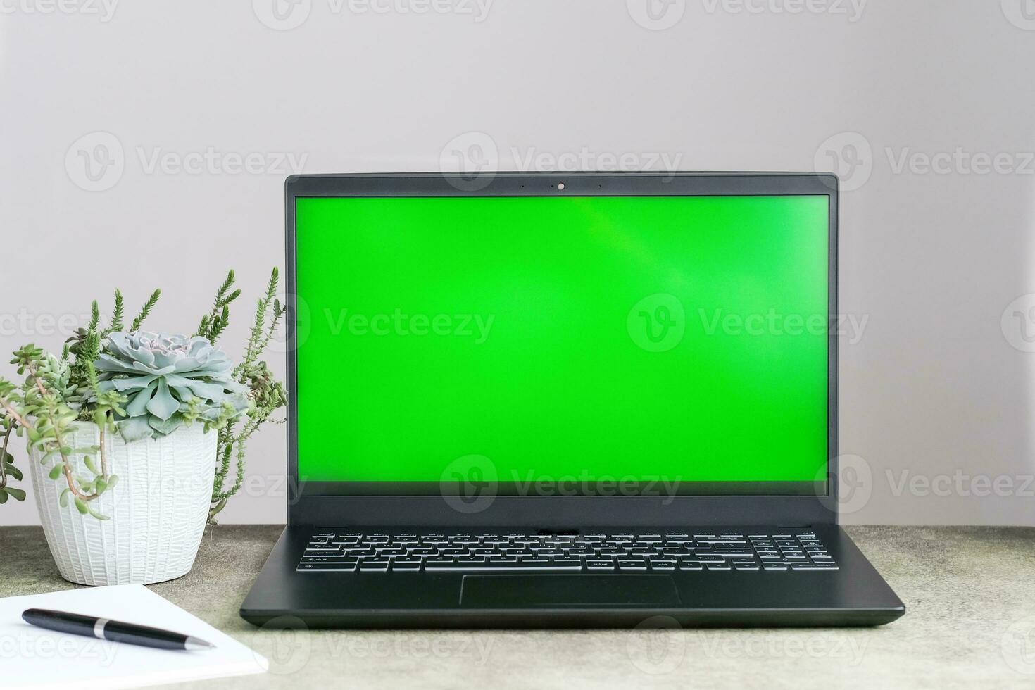 Mockup of laptop computer with empty green screen on table photo