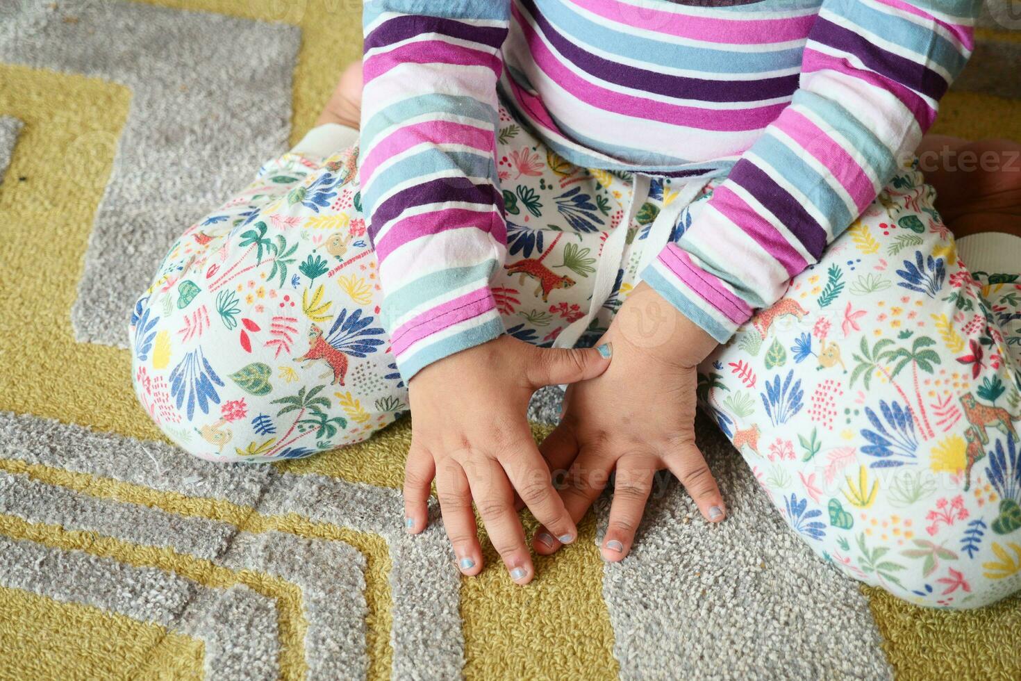child sitting W posture on the floor . photo