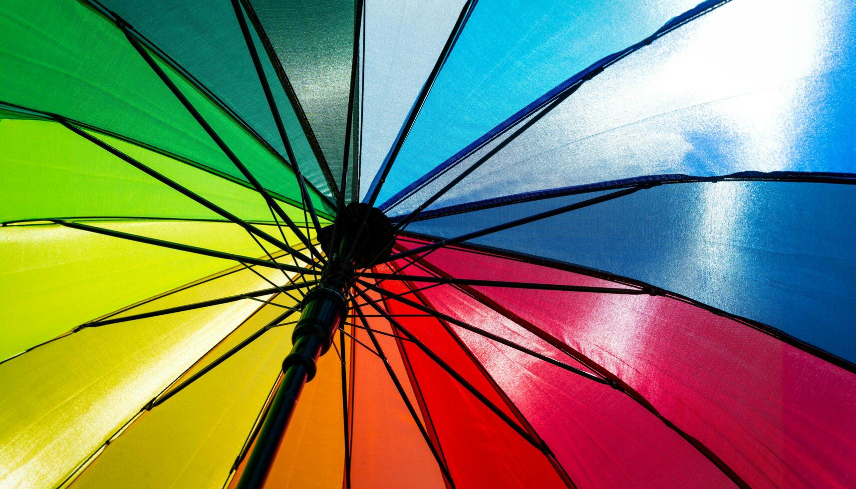 Colorful rainbow umbrella on blue sky background. LGBT, Pride Month, diversity, Sunprotect Concept. photo