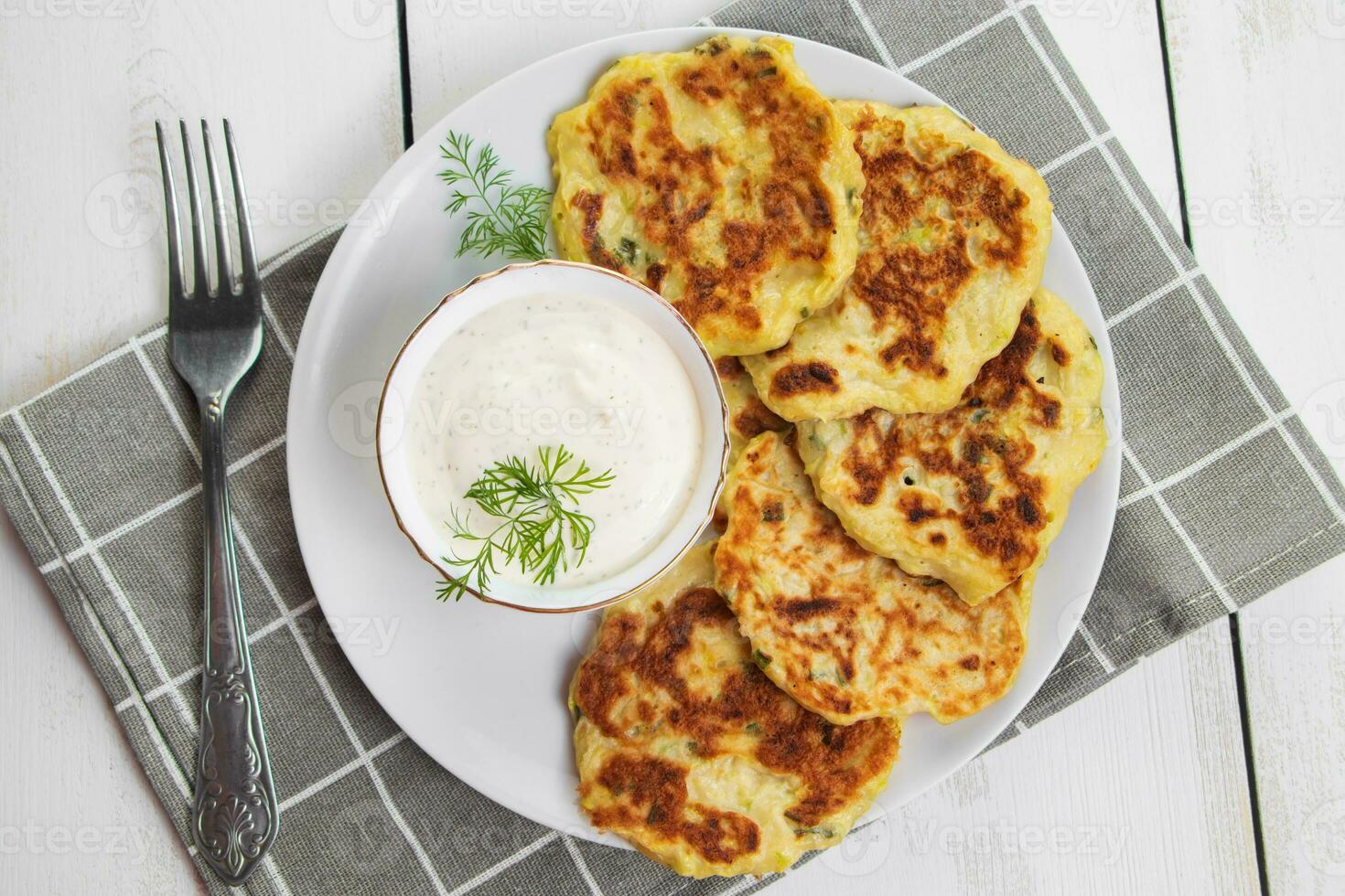 tortitas de calabacín con salsa de crema en el plato. comida de dieta saludable. ajuste de la mesa de la cena. foto