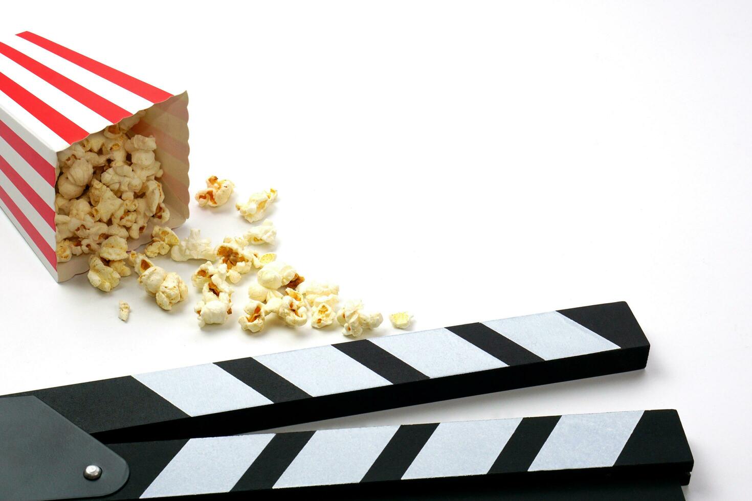 Clapperboard or movie slate black color with popcorn on white background. Cinema industry, video production and film concept. photo