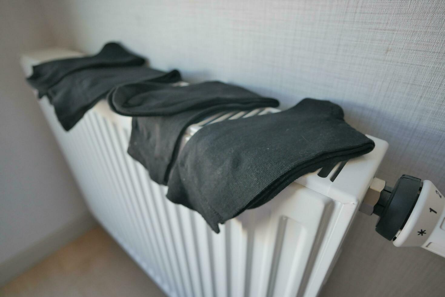 black color sock drying on heating radiator, photo