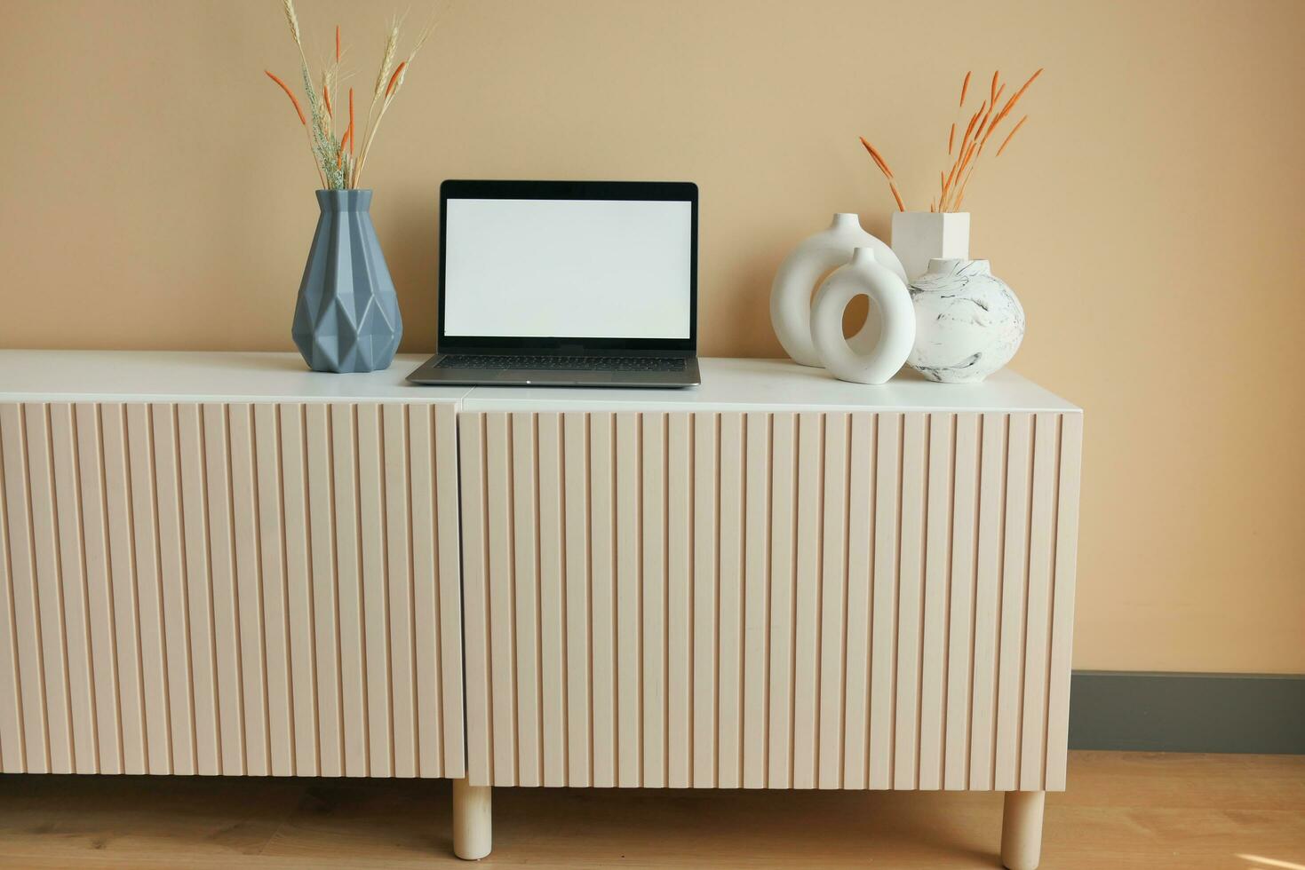 laptop with white screen on a cabinet in front of the empty clean wall photo