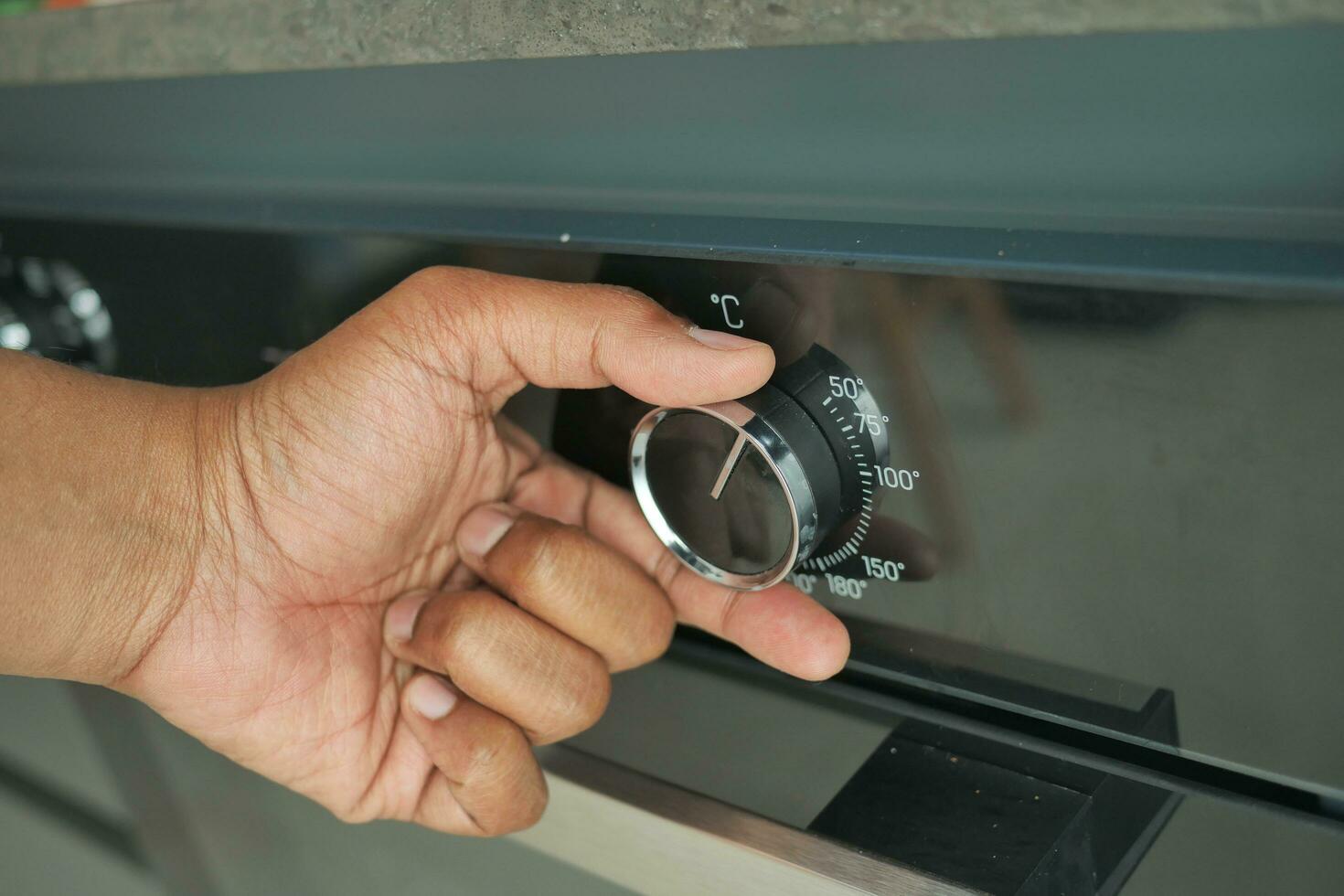 woman hand setting temperature control on oven. photo