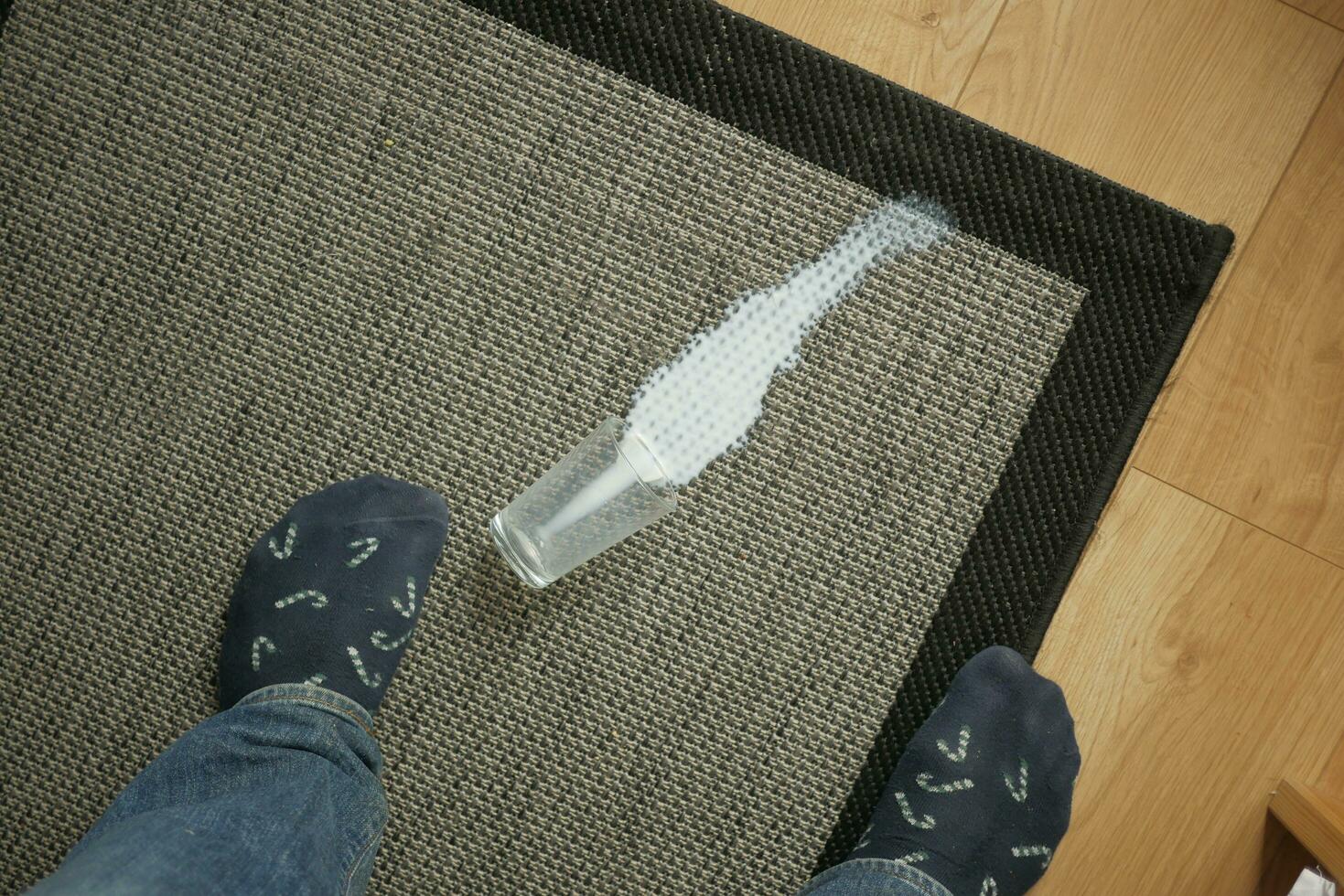 glass of milk spilled on gray color carpet photo