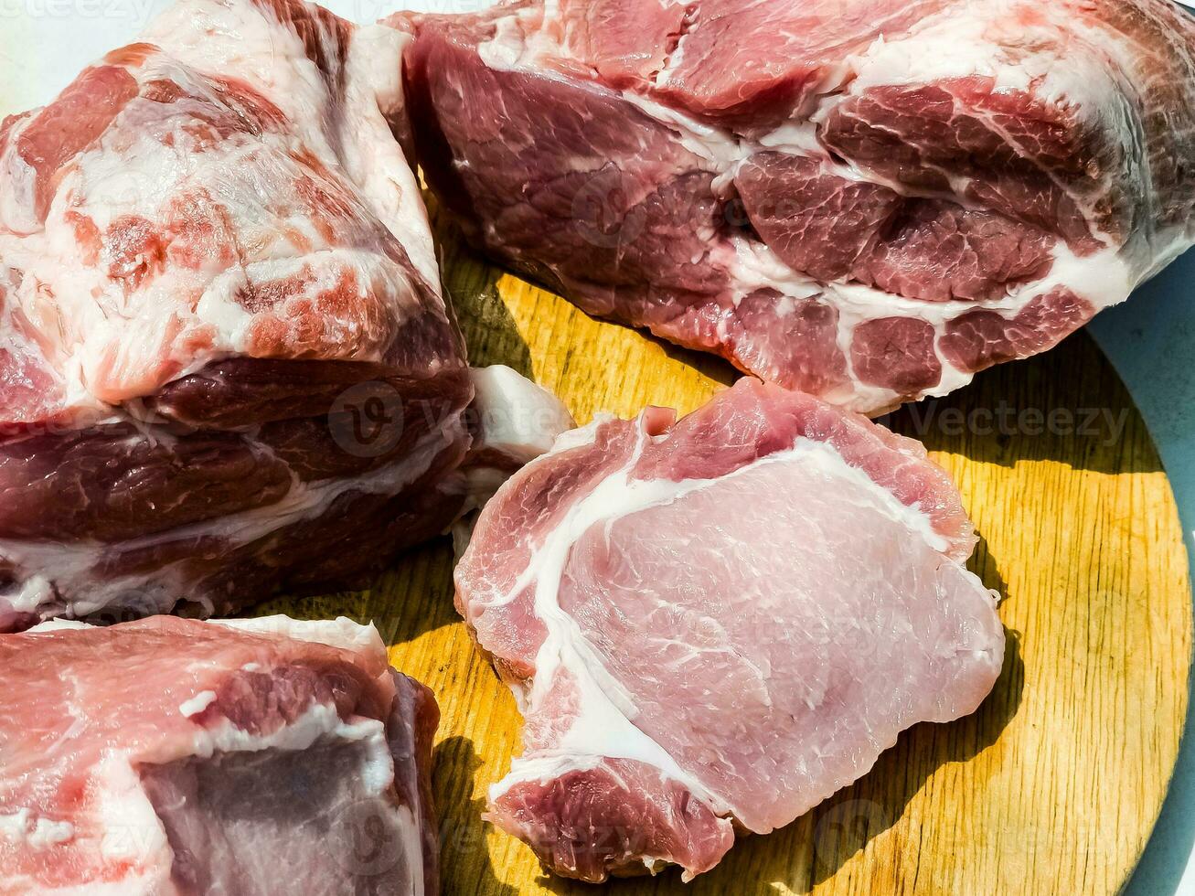 Fresh cuts of various parts of a pig carcass on a wooden kitchen board. Pieces of pig meat close-up photo