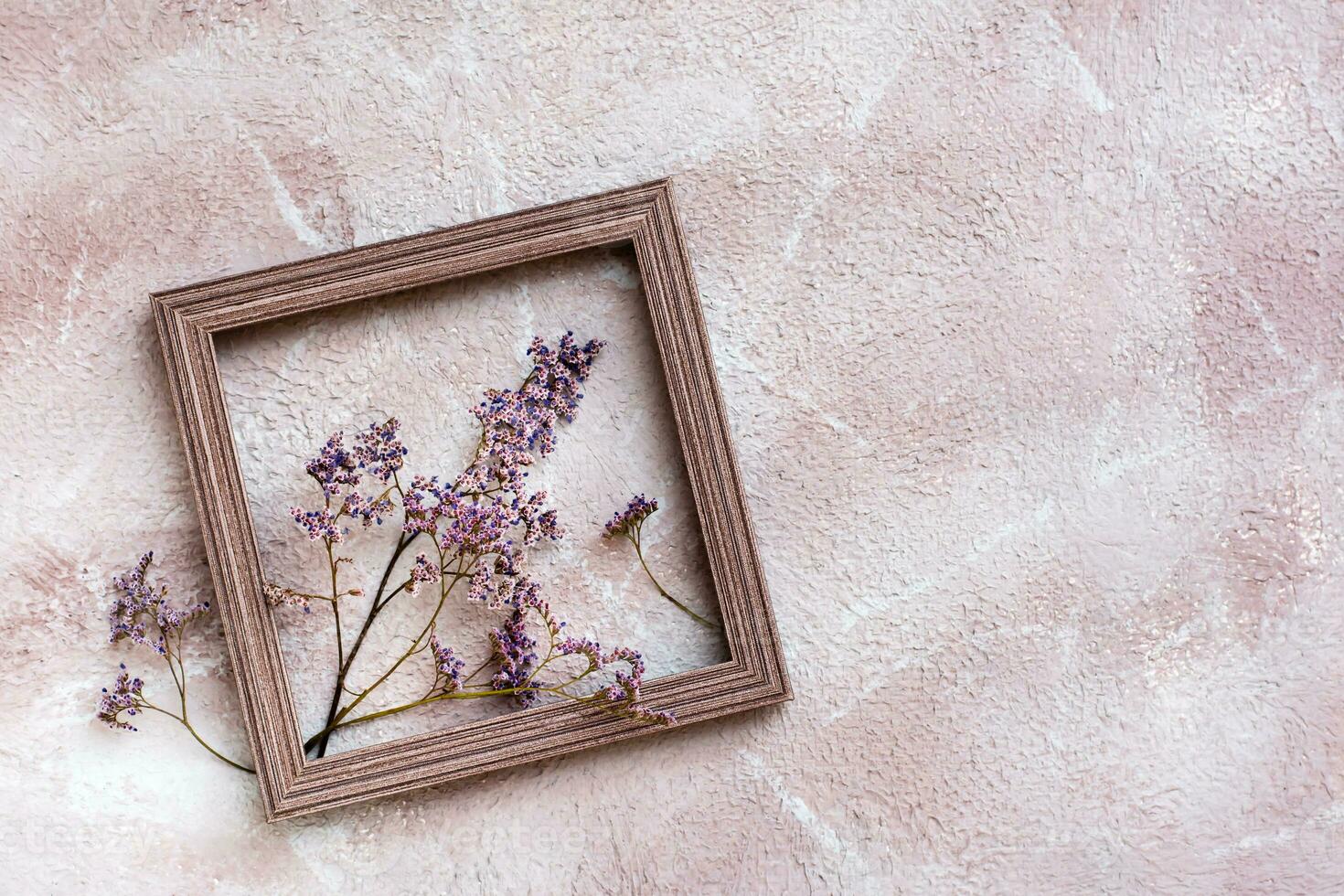 Dry purple flowers in a wooden frame on a textured background. Romantic greeting vintage card. Top view. Copy space photo