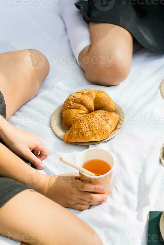 Eco-friendly picnic for schoolchildren in the park. Croissants on eco paper plates and apple juice in an eco cup with a straw on a white blanket. Back to school concept photo