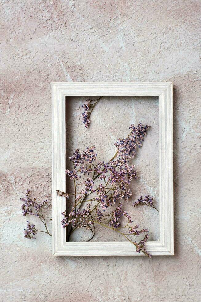 Dry purple flowers in a wooden frame on a textured background. Romantic greeting vintage card. Top and vertical view photo