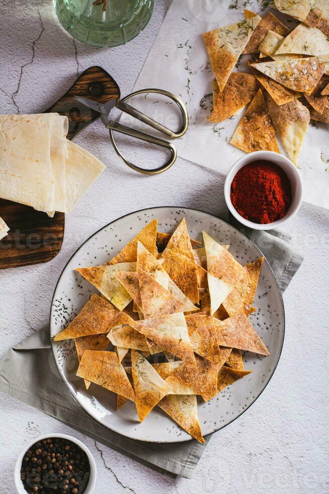 Spicy chips with paprika and dill from tortilla on a plate top and vertical view photo