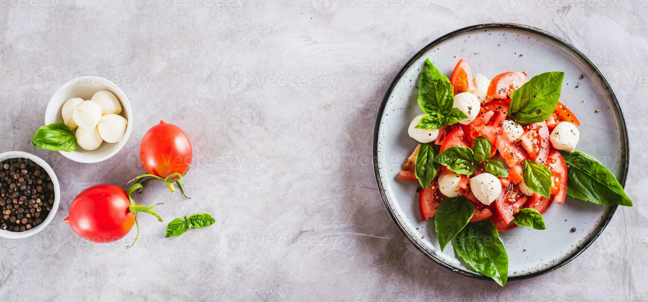 Delicious caprese salad with ripe tomatoes, mozzarella cheese and basil on a plate top  view web banner photo