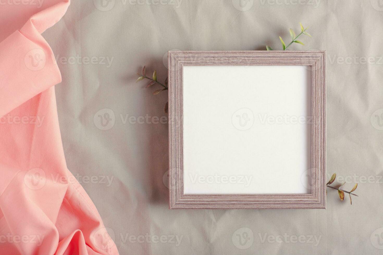Mockup empty photo frame and branches on green cotton fabric top view
