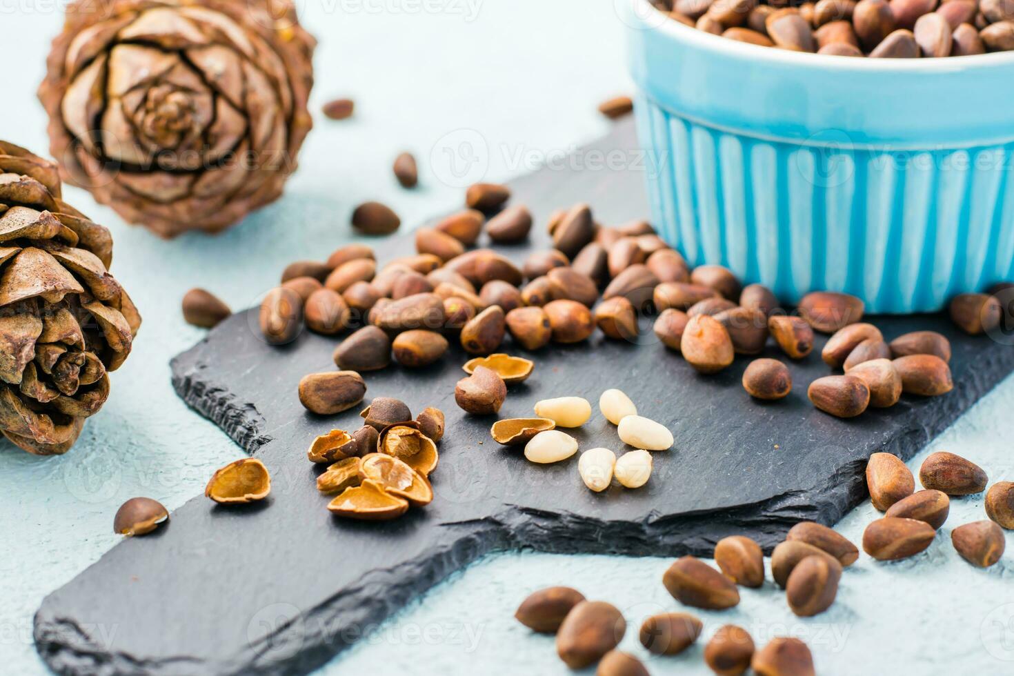 Several peeled pine nuts among in-shell nuts on a slate board. Remedy for insomnia and detox food. Vitamins and health photo