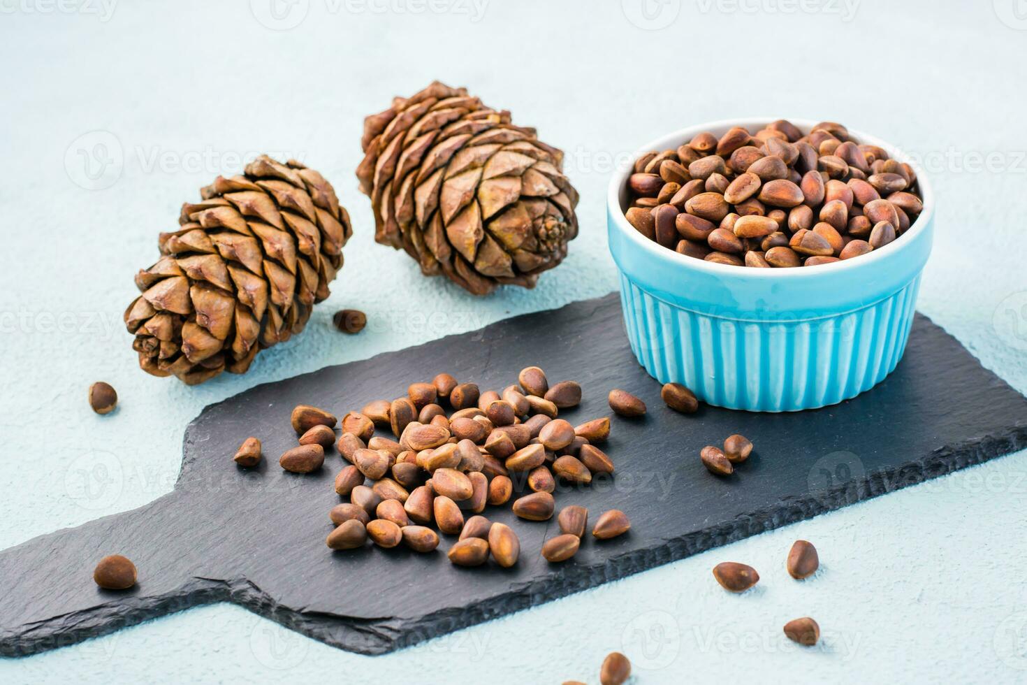 Unpeeled pine nuts and cones on a slate board and in a bowl. Gifts of Siberia. Detox and cure for insomnia. Healthy vitamin nutrition photo