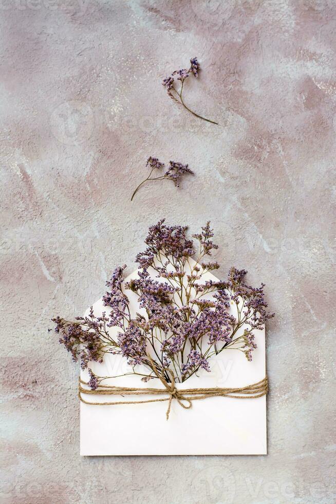 un ramo de flores de seco flores en un ligero sobre atado con un cuerda en un texturizado antecedentes. saludo romántico tarjeta. parte superior y vertical ver foto