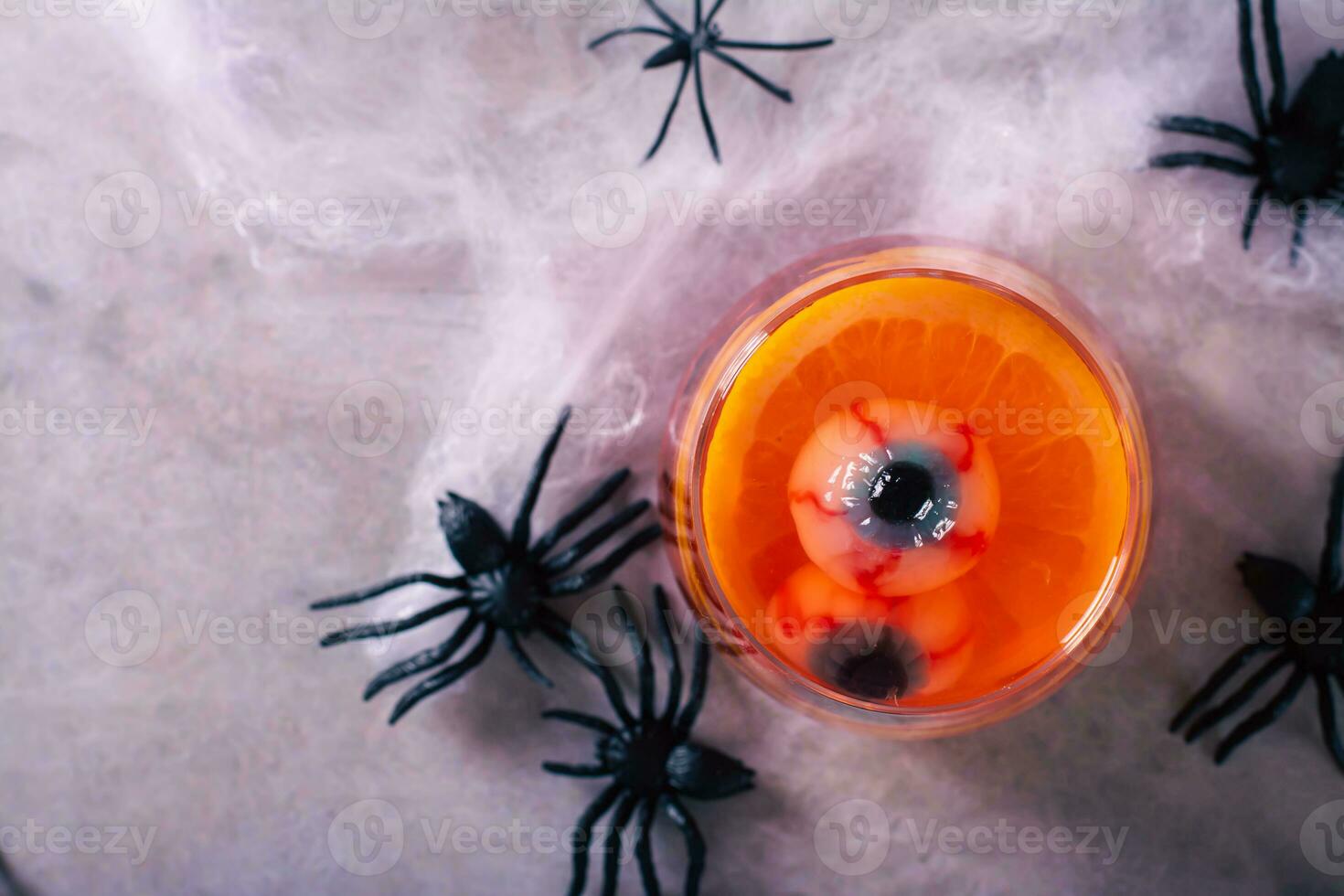 Close up of non alcoholic red cocktail with eyeballs and orange in glasses on the table top view photo