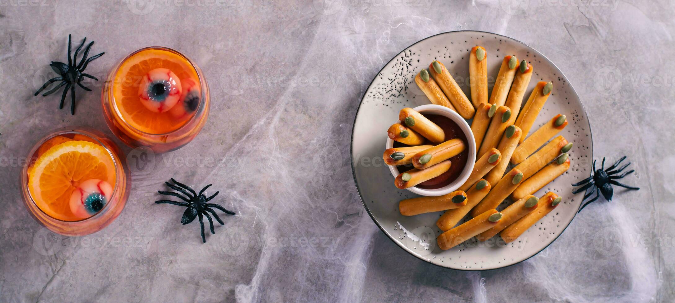 Halloween savory breadsticks with pumpkin seed nails on ketchup on a plate top view web banner photo