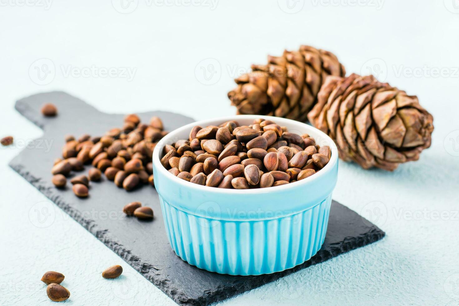 A bowl of unpeeled pine nuts and pine cones on a slate board. Detox and cure for insomnia. Healthy vitamin nutrition photo