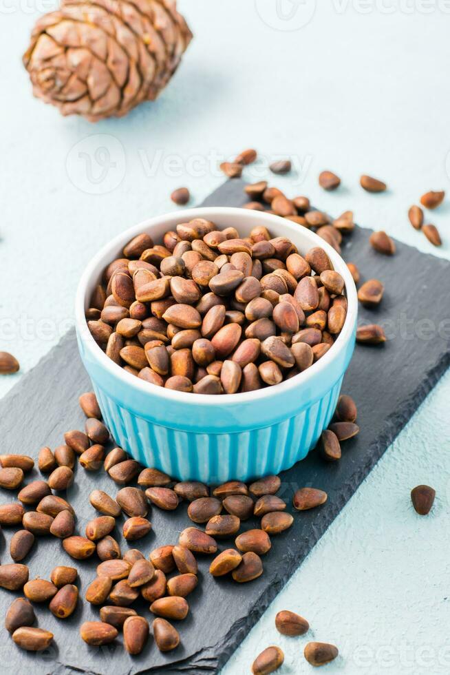 A bowl of unpeeled pine nuts on a slate board. Detox and cure for insomnia. Healthy vitamin nutrition photo