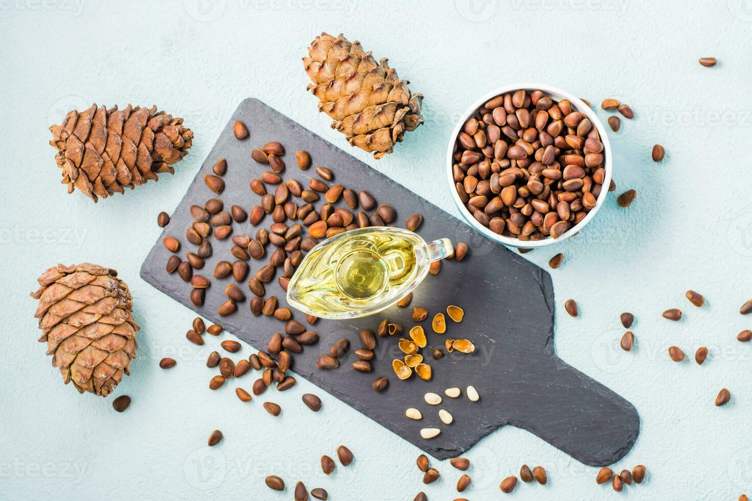 Fresh pine nut oil, nuts in a bowl and on a slate board. Remedy for insomnia and detox food. Vitamins and health. Top view photo