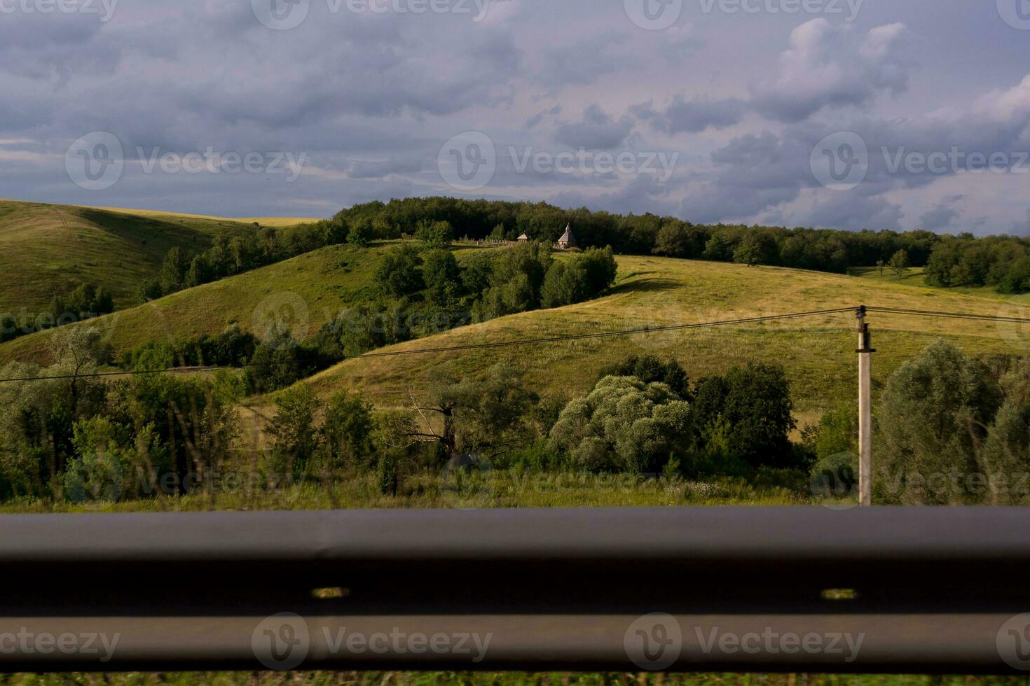 view of the green hills and the road fence photo