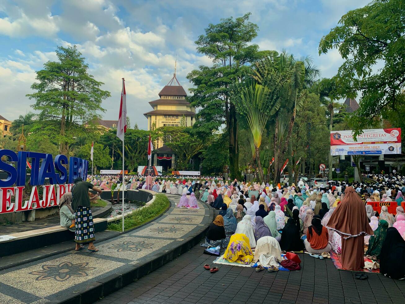 sholat idul fitri. indonesian muslim community are doing eid al fitr prayer in outdoor area. sholat idul adha in college field with words means independent college photo