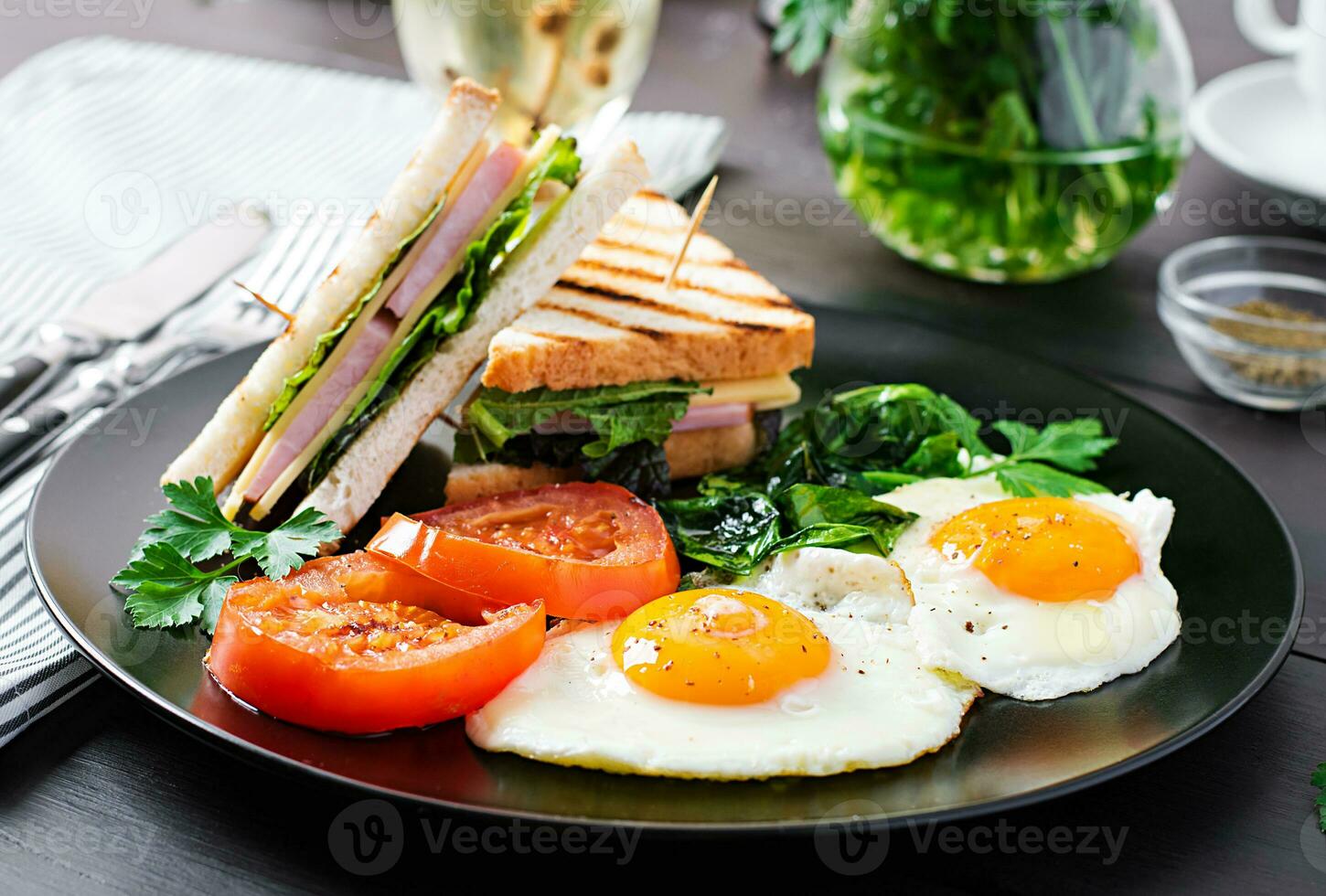 Breakfast. fried egg, spinach, tomatoes and club sandwich on plate. photo