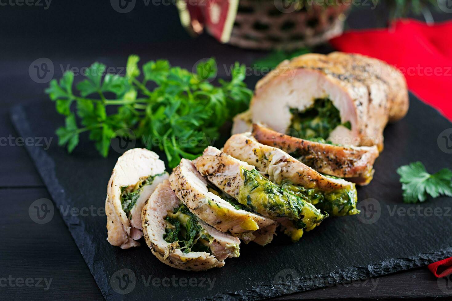 Roasted sliced Christmas roll of turkey with spinach and cheese on dark rustic background.  Festival food. photo