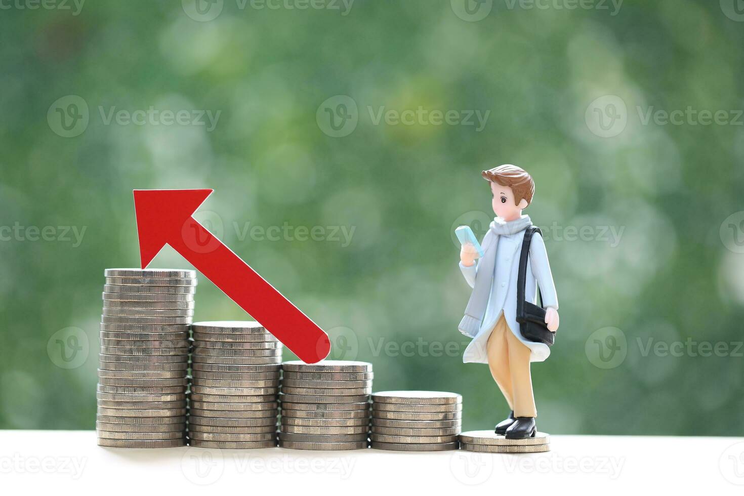 Business man standing on stack of coins money and red arrow graph on natural green background, investment and business concept photo