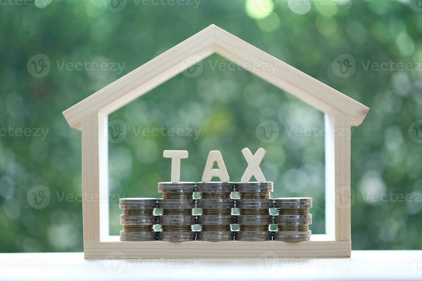 Estate tax,Model house with stack of coins money and tax word on green background,Business investment and Property tax concept photo