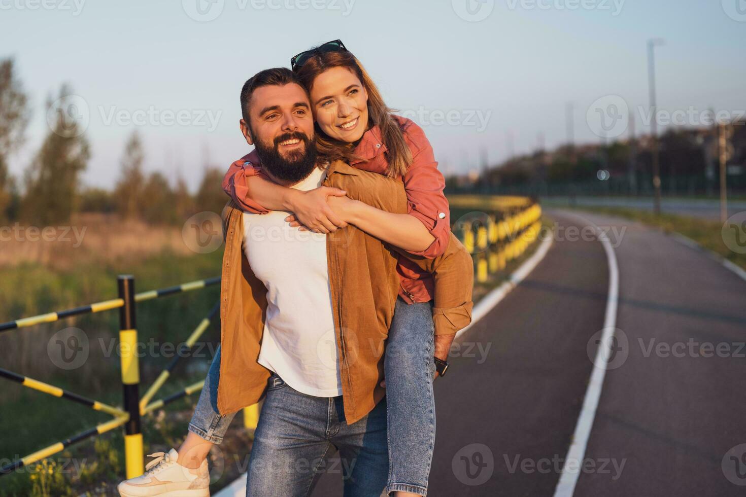 contento sonriente Pareja disfrutando puesta de sol. hombre es que lleva en espalda su mujer. foto