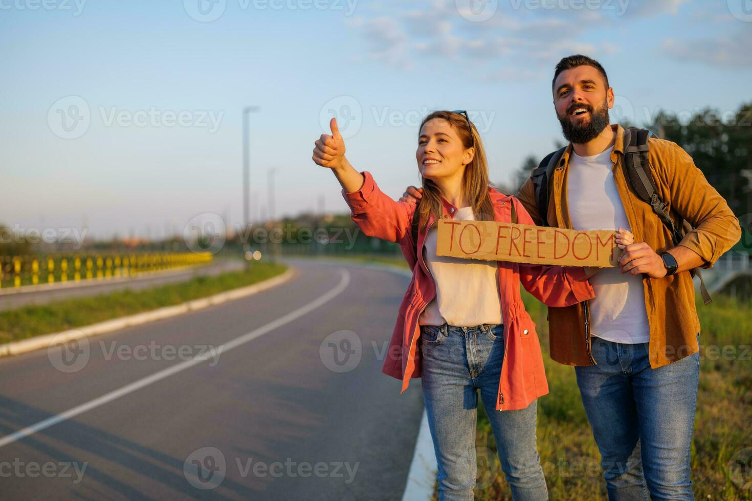 contento Pareja autoestop en borde del camino molesto a detener coche. ellos son participación cartulina con inscripción. foto