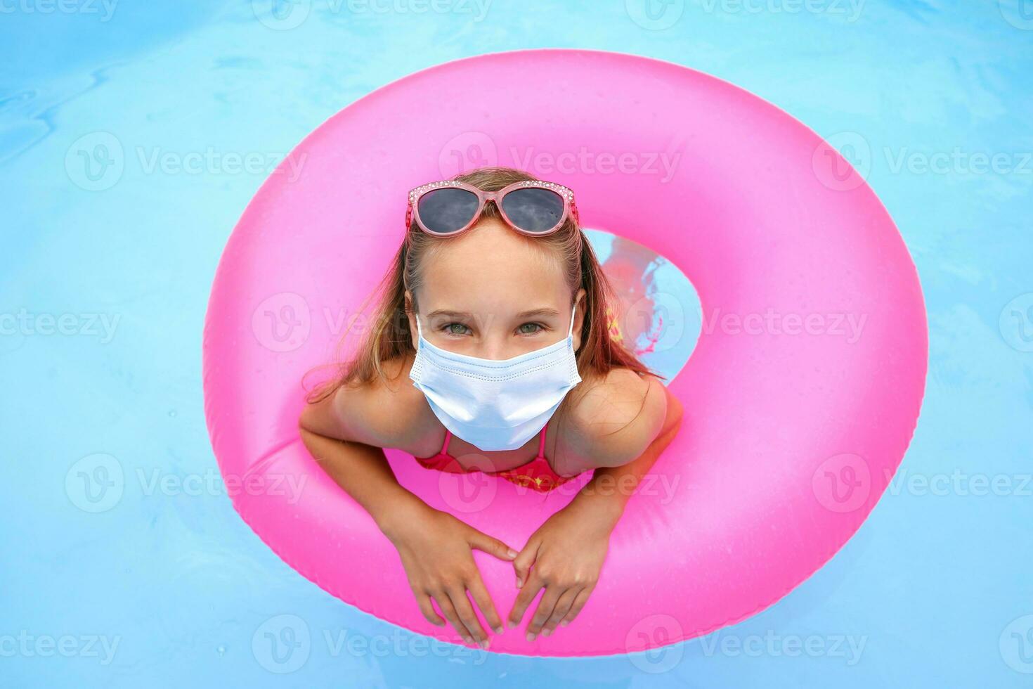 Girl with medical mask on her face in pool. photo