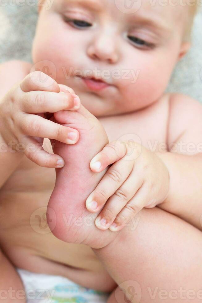 kid holds leg and looks at her photo